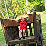 boy, casual, child, daytime, forest, grass, nature, outdoor, park, person, playground, red_clothing, shoes, shorts, spiderman, summer, sunlight, trees, wooden_cart, young