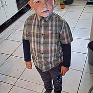 Almanzo participe au concours pour gagner de l'argent avec cette photo : child, boy, face_paint, plaid_shirt, long_sleeve, socks, kitchen, tile_floor, trash_bin, cactus_decoration, sunglasses, window, cabinet, oven, utensils, countertop, white_wall, indoor, standing, casual_clothing