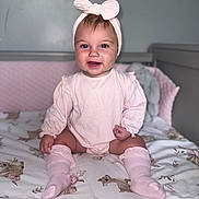 Ivy-Jean joined the competition — help win amazing prizes! baby, child, smiling, pink_clothing, headband, bow, knee_socks, crib, blanket, deer_pattern, floral_pattern, indoor, nursery, soft_lighting, portrait, cute, happy, sitting, infant, person