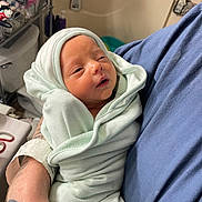 Parker is registered to the contest to win money with this photo: newborn, baby, swaddle, blanket, infant, person, arm, tattoo, hospital, soft, clothing, bedroom, care, resting, cute, wrapped, sleepy, human, tender, comfort
