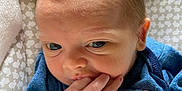 Parker joined the competition — help win amazing prizes! baby, infant, face, hand, fingers, blue_clothing, toy, plush, close_up, patterned_background, cute, skin, head, expression, newborn, indoors, soft_texture, portrait, young_child, toddler