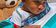 Tamir joined the competition — help win amazing prizes! toddler, child, baby_walker, toy, teddy_bear, indoor, curly_hair, earring, pensive, furniture, wood_paneling, carpet, clothing, close_up, hand, face, person, childhood, playtime, cute