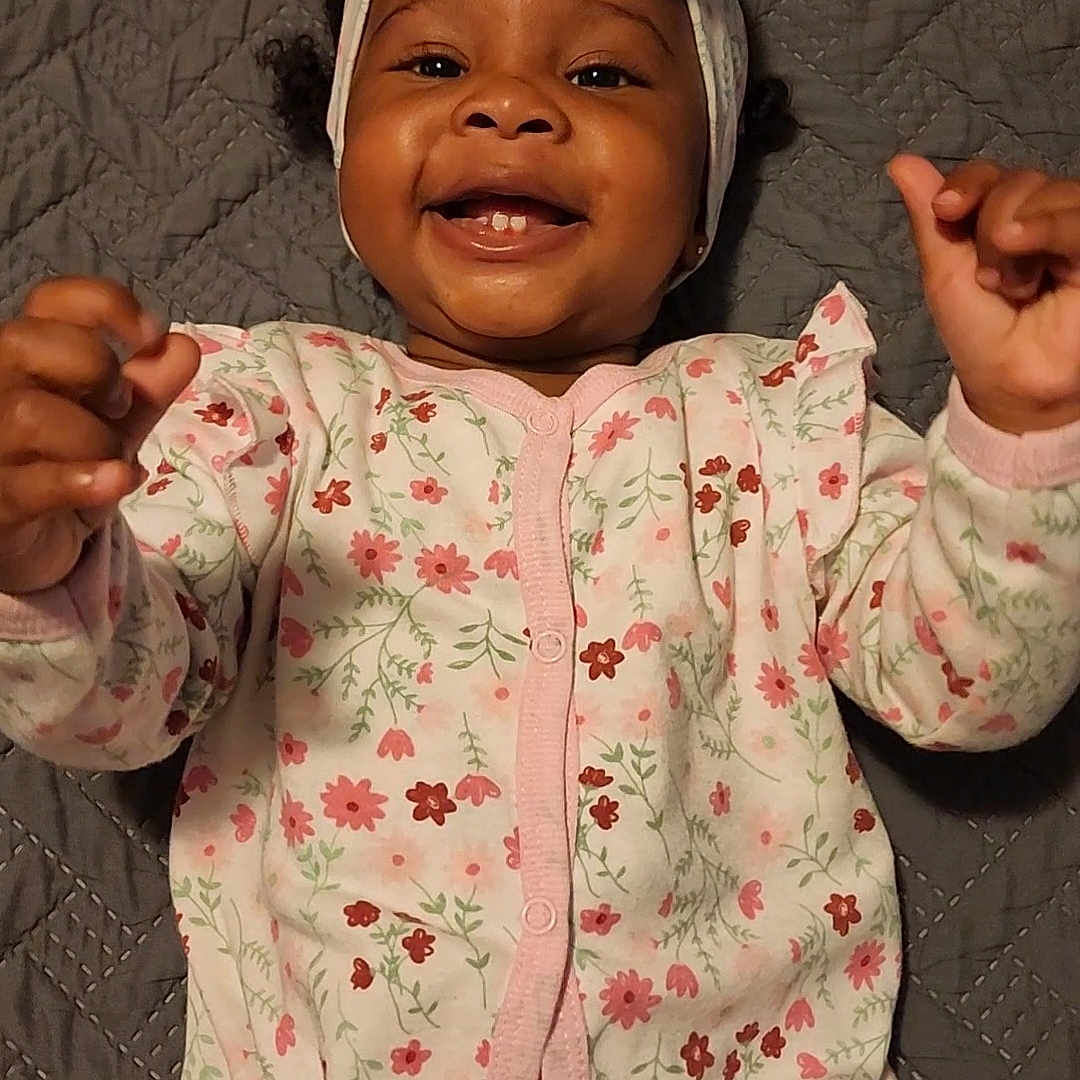 Zuri is registered to the contest to win money with this photo: baby, babylaughing, bodypart, bonnet, cap, clothing, coat, face, finger, hand, happy, hat, head, jacket, laughing, pajamas, person, photography, portrait, smile