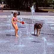 Kira a rejoint le concours — aidez-le/la à gagner de superbes lots ! animal, barefoot, child, dog, fun, leash, nature, outdoor, park, playful, recreation, splash_park, summer, sunny_day, swimsuit, trees, water_fountains, water_spray, wet_dog, young_girl