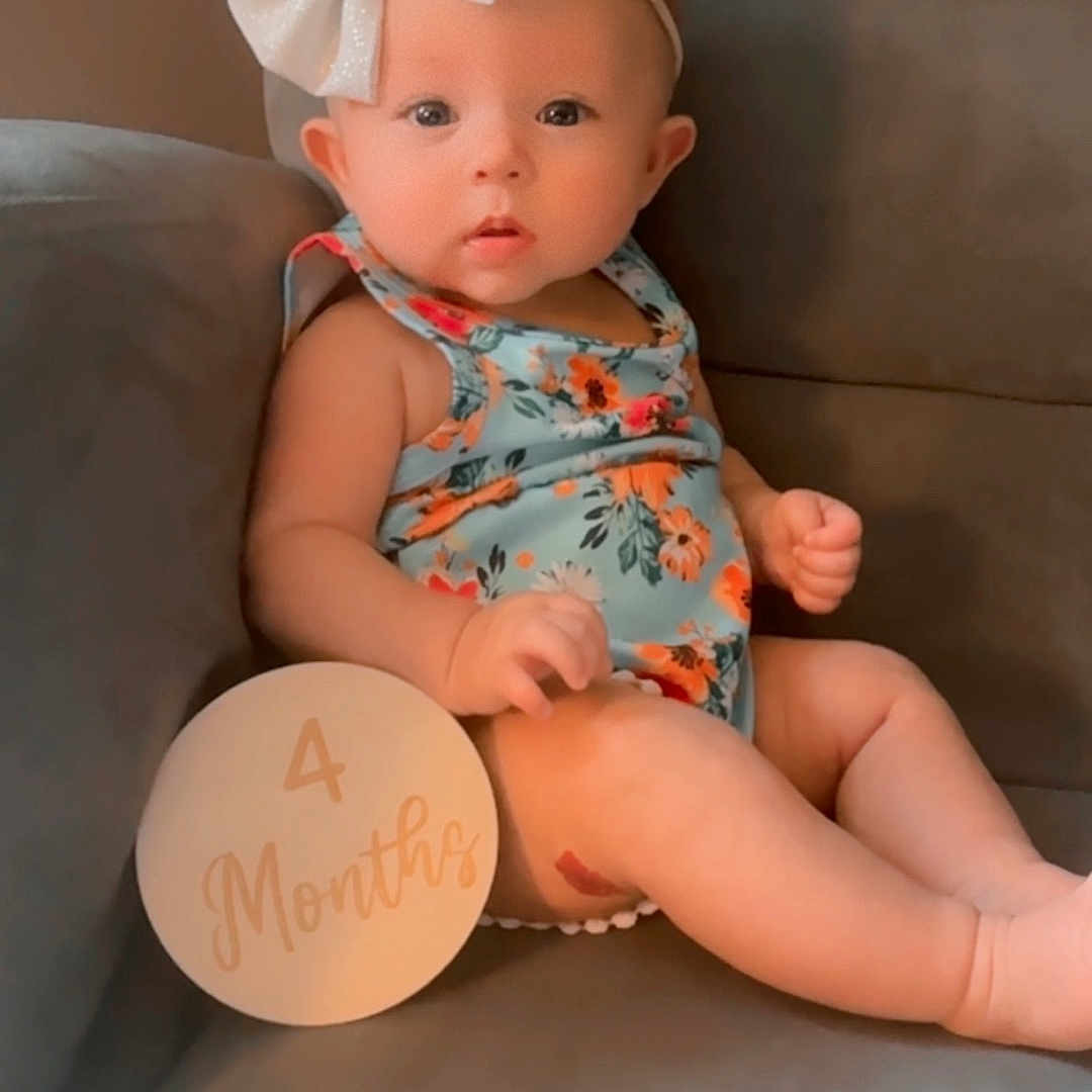 Oaklyne is registered to the contest to win money with this photo: 4_months, baby, bow, child, couch, cute, expression, face, floral_outfit, hand, headband, indoor, infant, legs, person, portrait, sign, sitting, skin, soft_lighting