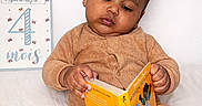Foulaydi participe au concours pour gagner de l'argent avec cette photo : baby, child, infant, reading, book, corduroy, pajamas, milestone_card, 4_months, white_background, sitting, indoors, cute, young, portrait, cozy, hand, face, expression, education
