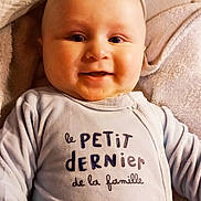 Arthur participe au concours pour gagner de l'argent avec cette photo : baby, smiling, face, infant, child, clothing, blanket, soft_texture, cute, portrait, happy, lying_down, cheeks, eyes, long_sleeves, text_on_clothing, cozy, indoors, person, head