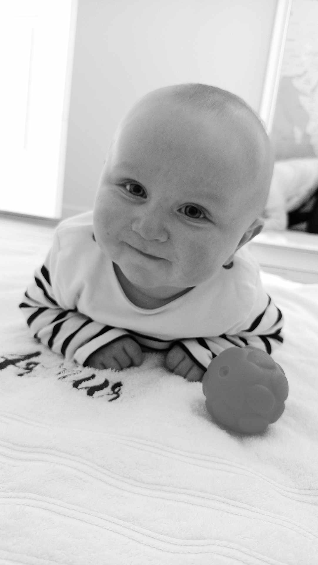 Arthur participe au concours pour gagner de l'argent avec cette photo : baby, infant, smile, face, striped_clothing, toy, ball, towel, lying_down, indoors, cute, child, portrait, black_and_white, soft_texture, hands, eyes, head, small, young
