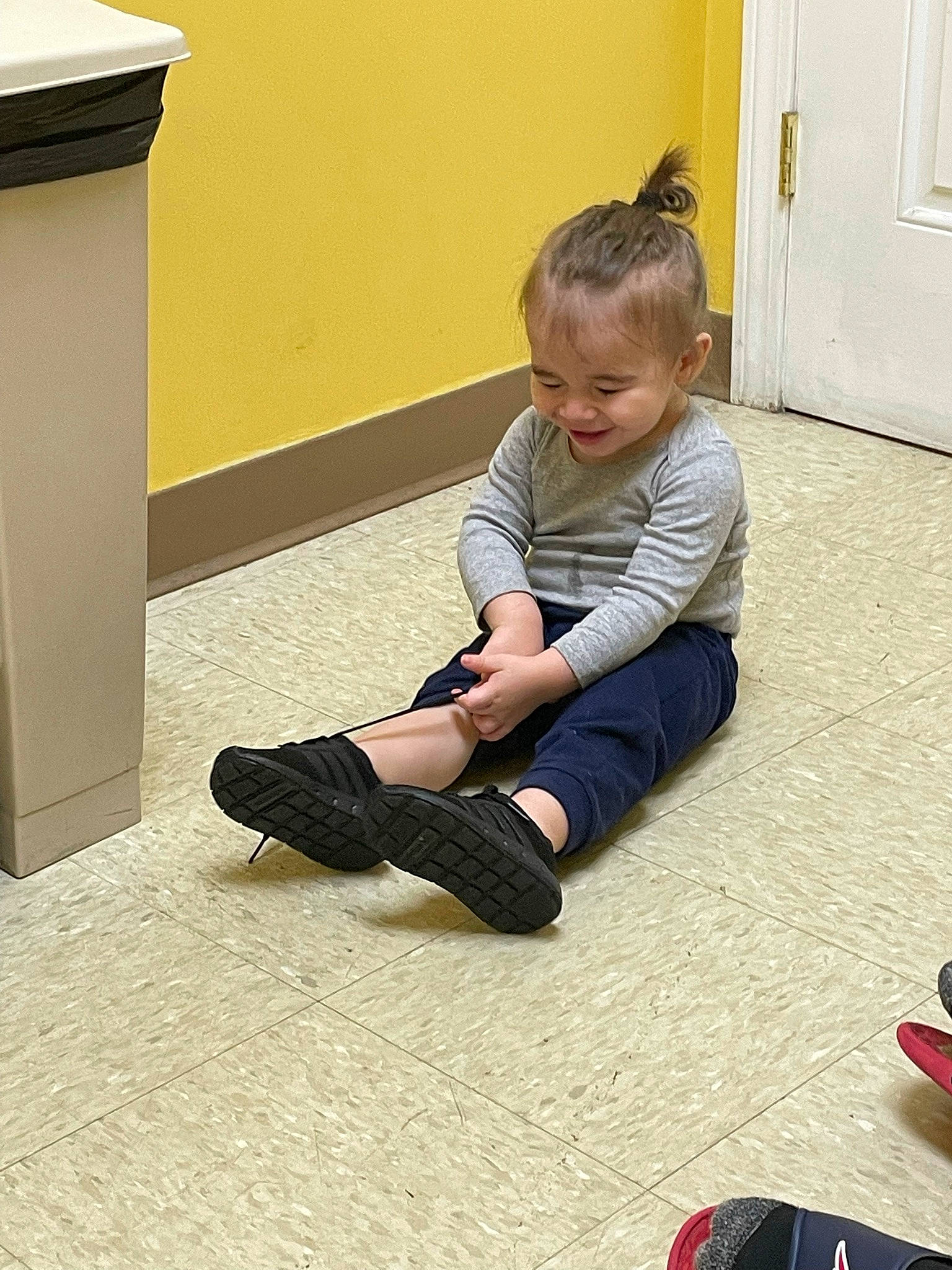 Jaidyn joined the competition — help win amazing prizes! calf, child, door, floor, flooring, foot, footwear, hardwood, human_leg, joint, joy, knee, person, shoe, sitting, smile, sock, standing, thigh, toddler