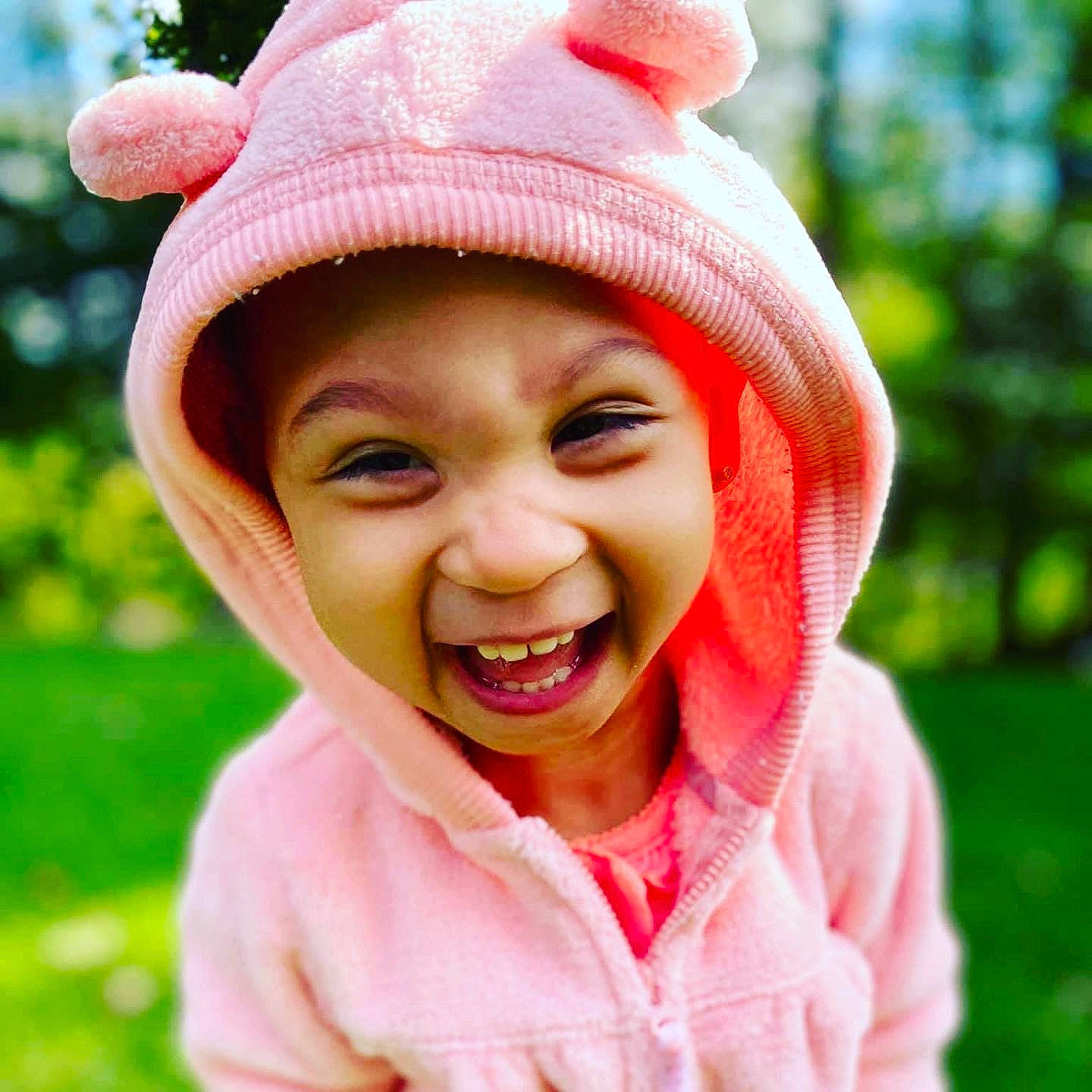 Amiya is registered to the contest to win money with this photo: baby_laughing, cap, child, eye, face, fun, grass, happy, headgear, headwear, human_body, jaw, joy, leisure, lip, nose, people_in_nature, person, pink, red