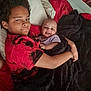 Diamond is registered to the contest to win money with this photo: child, baby, bed, blanket, red, black, smile, happy, sibling, toddler, person, clothing, hair, pillow, indoor, face, hug, lying_down, comfort, cozy