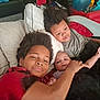 Diamond is registered to the contest to win money with this photo: child, baby, siblings, couch, pillow, blanket, smile, indoor, casual_clothing, curly_hair, infant, happy, relaxing, family, toddler, play_area, red_chair, blanket_wrap, portrait, cozy