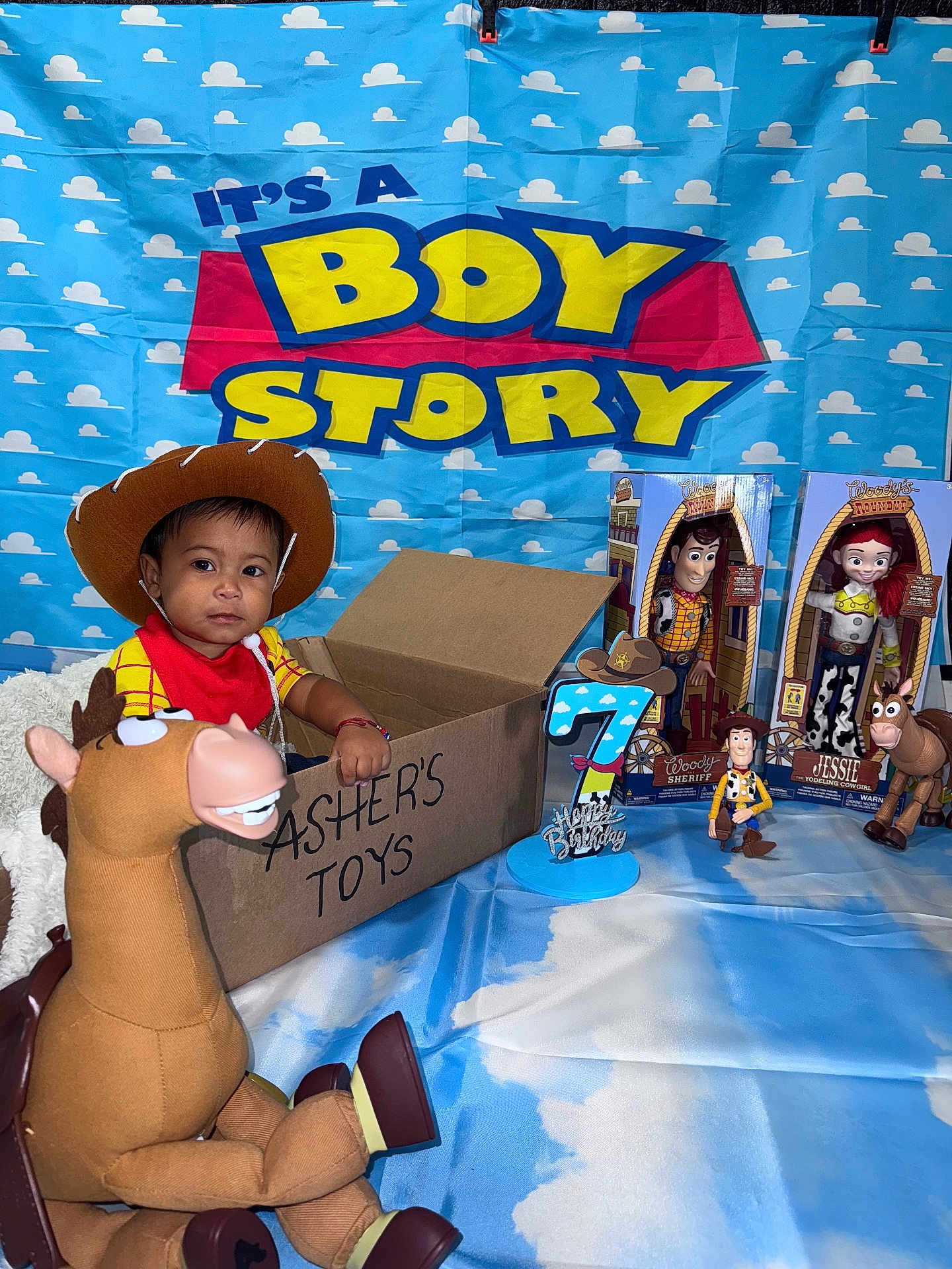 Asher Javier joined the competition — help win amazing prizes! toddler, child, toy_story, woody, jessie, bullseye, toy, cardboard_box, birthday_candle, birthday, cowboy_hat, red_bandana, blue_backdrop, cloud_pattern, smiling_child, indoor, celebration, birthday_party, person, toys