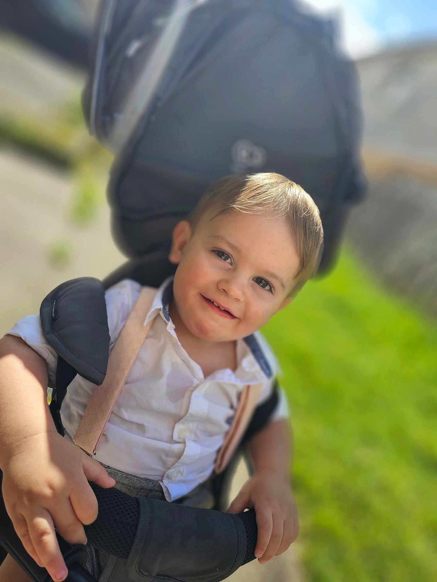 Sonnie-Lee joined the competition — help win amazing prizes! toddler, child, smile, stroller, outdoor, sunlight, grass, white_shirt, suspenders, happy, face, hands, portrait, baby, young_child, daylight, greenery, casual_clothing, closeup, cute
