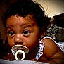 Vyraih is registered to the contest to win money with this photo: baby, pacifier, curly_hair, close_up, blanket, indoor, child, cute, infant, face, expression, person, patterned_clothing, earring, soft_toys, resting, young_child, sleepwear, comfort, home