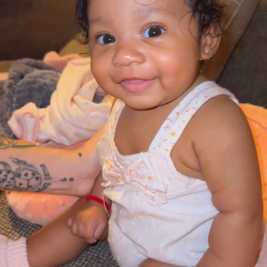 Vyraih is registered to the contest to win money with this photo: arm_tattoo, baby, blanket, child, clothing, couch, cozy, cute, hair_clip, happy, indoor, infant, person, pink, portrait, sitting, skin, smile, socks, soft_lighting