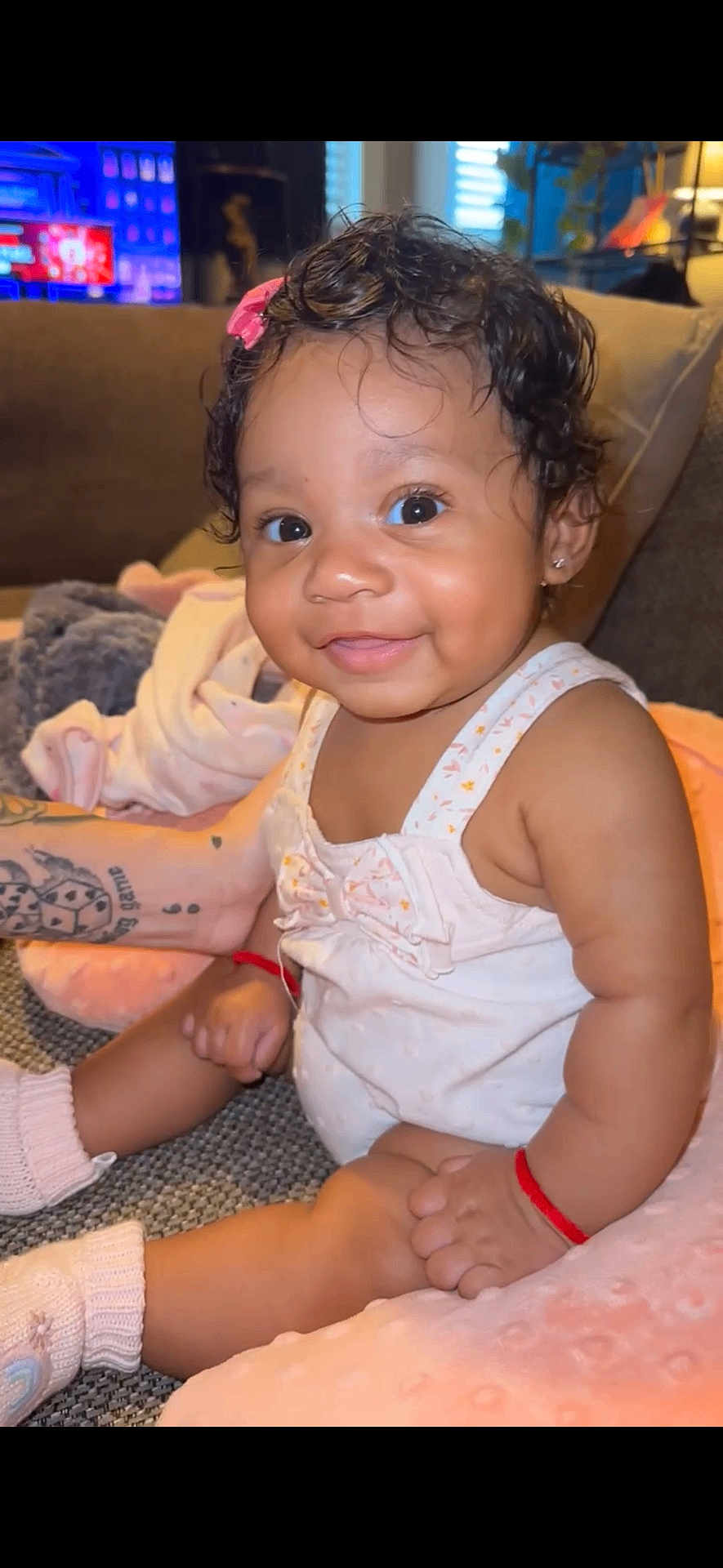 Vyraih is registered to the contest to win money with this photo: baby, smile, child, cute, indoor, couch, blanket, hair_clip, socks, arm_tattoo, happy, portrait, infant, soft_lighting, cozy, skin, person, sitting, pink, clothing