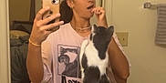 Earl is registered to the contest to win money with this photo: bathroom, black_and_white_cat, casual_clothing, cat, countertop, door, home, interaction, interior, mirror, pet, phone, playful, reflection, selfie, sink, standing_cat, towel, woman, young_adult