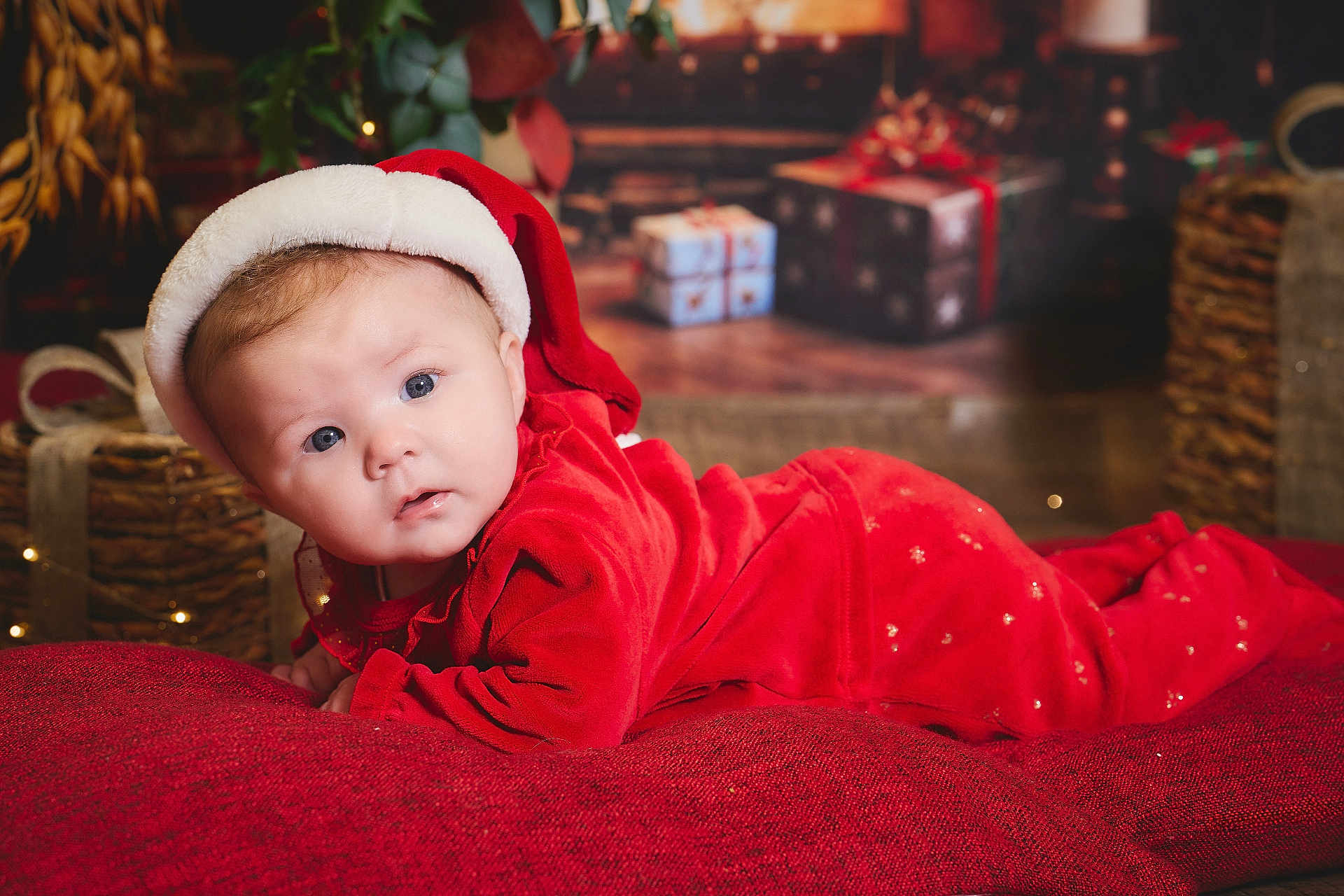 Lylou participe au concours pour gagner de l'argent avec cette photo : baby, infant, santa_hat, red_clothing, christmas, holiday, festive, blanket, face, blue_eyes, cute, indoors, decorations, gift_boxes, soft_lighting, portrait, toddler, holiday_season, cozy, smiling