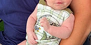 Krue Burgess is registered to the contest to win money with this photo: adult, baby, beige_shorts, blue_shirt, clothing, comfort, feet, fingers, gentle_touch, hand, head, infant, legs, outdoor, person, plaid, romper, sitting, skin, watch