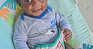 Syair Hayes is registered to the contest to win money with this photo: baby, baby_seat, child, clothing, colorful, cute, face, floor, hand, happy, indoor, infant, legs, pattern, playful, portrait, shark, shirt, sloth, smiling