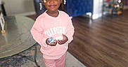 Niyara Hayes is registered to the contest to win money with this photo: child, girl, pink_clothing, standing, indoor, living_room, carpet, toy, smiling, hair_bows, wood_floor, furniture, casual, portrait, young_child, home, person, cute, happy, decor
