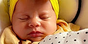 Delilah is registered to the contest to win money with this photo: baby, sleeping, blanket, headband, yellow, polka_dot, bow, face, infant, cozy, cute, child, soft, closeup, indoor, rest, peaceful, apparel, person, newborn