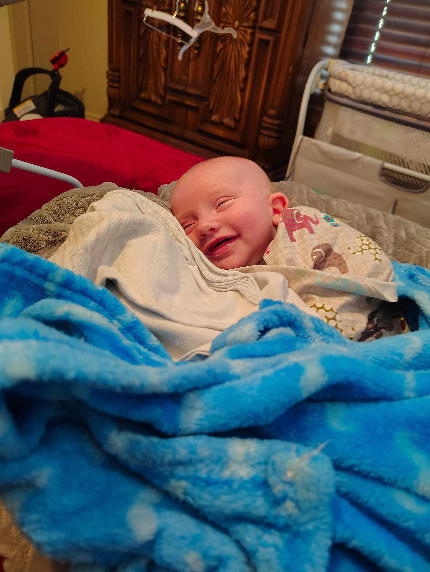 Lyric is registered to the contest to win money with this photo: baby, smiling, blanket, bed, wooden_cabinet, crib, indoors, happy, infant, clothing, cozy, child, fabric, furniture, head, human, person, portrait, resting, toddler