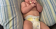 Nolan is registered to the contest to win money with this photo: baby, diaper, cushion, striped, baby_food, chewing, infant, person, tattoo, arm, blanket, bed, skin, hand, foot, indoor, closeup, cute, resting, comfort