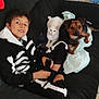 Pocket participe au concours pour gagner de l'argent avec cette photo : child, boy, cat, dog, couch, remote_control, black_clothing, skeleton_costume, white_cat, brown_dog, indoor, tile_floor, fabric, pet, smiling, sitting, looking_at_camera, home, cozy, relaxed