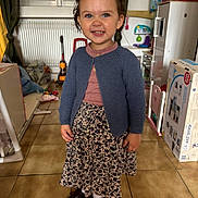 Alma a rejoint le concours — aidez-le/la à gagner de superbes lots ! blue_cardigan, cabinet, child, curtains, floral_skirt, girl, hands, happy, indoor, maroon_shoes, pigtails, play_kitchen, portrait, radiator, smiling, standing, tile_floor, toddler, toys, window