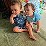 toddler, child, indoor, carpet, denim_overalls, blue_shirt, barefoot, water_bottles, green_carpet, curly_hair, sitting, crawling, wooden_furniture, person, floor, expression, household, footwear, candid, curiosity