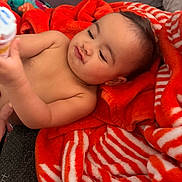 Haisley is registered to the contest to win money with this photo: baby, child, blanket, red, white, striped, pout, cute, face, expression, hand, indoor, soft_lighting, cozy, person, infant, skin, toy, playful, warm