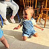 Haisley is registered to the contest to win money with this photo: toddler, child, denim_overalls, kneeling, sunlight, shadow, floor, elderly_person, walker, crocs, hands, wooden_chair, wooden_table, indoor, casual_clothing, smiling, curly_hair, home, person, furniture