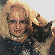 Simon joined the competition — help win amazing prizes! woman, cat, siamese_cat, glasses, pearl_necklace, bracelet, blonde_hair, long_hair, indoor, portrait, smiling, furry, blue_eyes, close_up, couch, sofa, jewelry, eyewear, pet, cozy