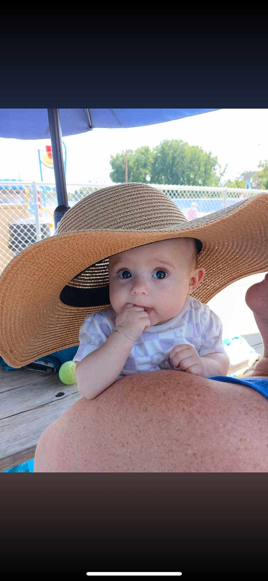 Elliana joined the competition — help win amazing prizes! baby, child, hat, sunhat, outdoor, shoulder, person, fence, trees, daylight, skin, face, eyes, hand, clothing, wood, table, summer, shade, curious