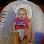 Elliana is registered to the contest to win money with this photo: baby, child, infant, smiling, sitting, baby_seat, clothing, red_shirt, face, head, person, indoor, cushion, comfort, happy, looking_at_camera, young_child, human, seat_belt, cheerful