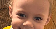 Alivia is registered to the contest to win money with this photo: baby, child, closeup, clothing, couch, cute, face, hair, happy, indoor, person, pony_tail, portrait, shirt, smile, sunflower, texture, toddler, yellow, young_child