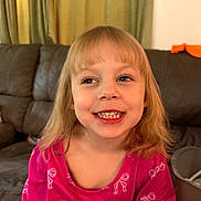 Alivia is registered to the contest to win money with this photo: blonde_hair, child, couch, cozy, curtains, cute, expression, face, girl, happy, home, indoor, long_sleeve, person, pink_clothing, portrait, room, sitting, smile, young