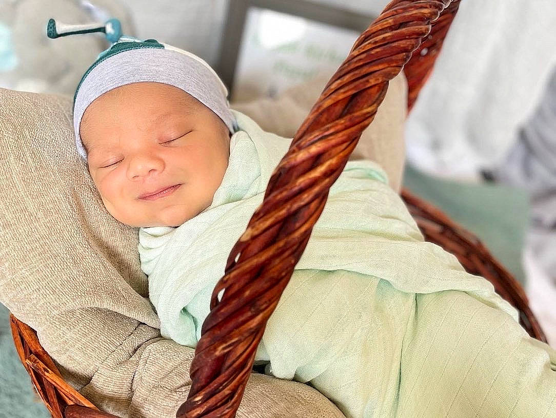 Elijah is registered to the contest to win money with this photo: baby, baby_toddler_clothing, cap, comfort, fashion_accessory, flesh, headwear, linens, peach, person, room, scarf, shawl, sleeve, thumb, toddler