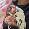 baby, infant, sleeping, blanket, swaddled, portrait, close_up, cozy, pink, clothing, hand, fist, hair, bow, peaceful, indoors, soft_focus, nap, bedding, child