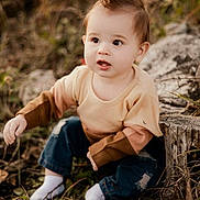 Wes is registered to the contest to win money with this photo: toddler, child, outdoor, grass, tree_stump, sweater, jeans, white_socks, curious, face, hair, nature, sitting, baby, person, young_child, autumn, casual_clothing, expression, exploring