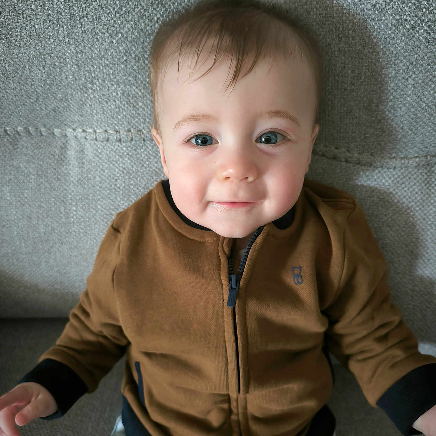 Abel participe au concours pour gagner de l'argent avec cette photo : baby, bodypart, clothing, coat, couch, face, finger, furniture, hand, happy, head, jacket, knitwear, longsleeve, pants, person, photography, portrait, sleeve, smile