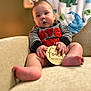 Ryder is registered to the contest to win money with this photo: baby, infant, toddler, child, sitting, couch, blanket, dinosaur_blanket, onesie, striped_clothing, red_text, milestone_sign, four_months, chubby_cheeks, bare_feet, portrait, indoor, soft_lighting, shallow_depth_of_field, curious_expression