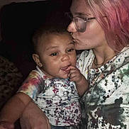 Myla joined the competition — help win amazing prizes! child, adult, glasses, pink_hair, kiss, affection, colorful_clothing, paint_splatter, indoor, portrait, person, family, love, close_up, casual_wear, happy, baby, candid, warmth, bond