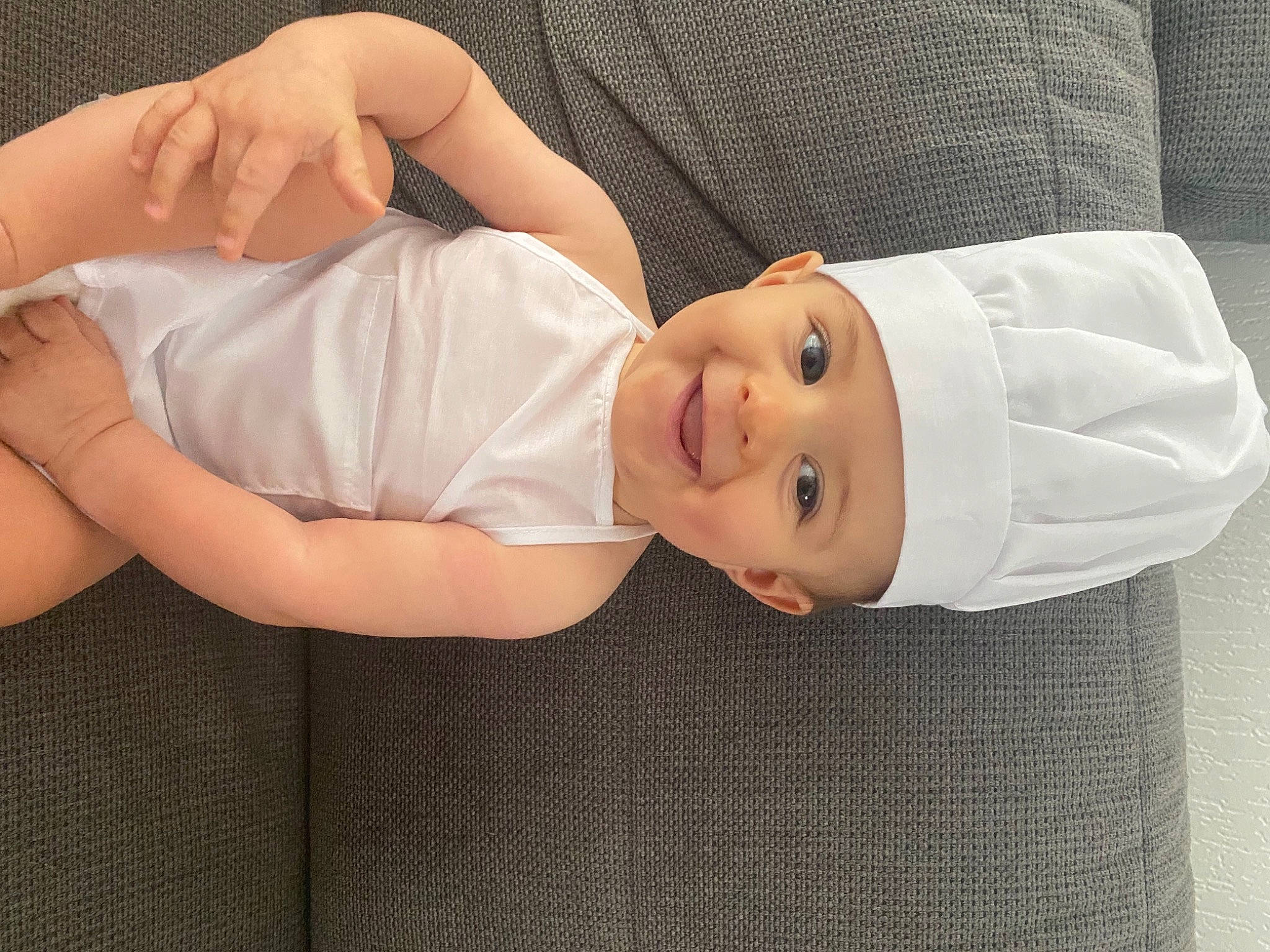 émilio participe au concours pour gagner de l'argent avec cette photo : baby_toddler_clothing, chest, child, comfort, dress, eye, eyelash, face, facial_expression, hat, head, headgear, headwear, joy, lip, person, skin, sleeve, smile, thigh