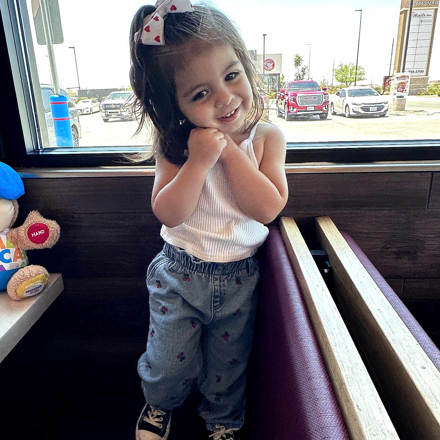 Jasmine Miamor joined the competition — help win amazing prizes! bench_seating, bow, cars, casual_clothing, child, cute, daylight, girl, hair_accessory, indoor, jeans, parking_lot, plush_toy, pose, restaurant, smile, sneakers, white_tank_top, window, wood_paneling