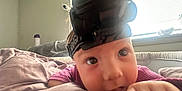 Oakley joined the competition — help win amazing prizes! baby, headlamp, blanket, indoor, child, face, curious, closeup, person, window, natural_light, soft_light, cozy, couch, pink_clothing, hand, expression, infant, home, relaxed