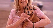 Sawyer is registered to the contest to win money with this photo: blurred_background, casual, dog, evening, friendly, glasses, happy, holding, nature, outdoor, pet, pink_dress, portrait, sidewalk, small_dog, smiling, sunset, tree, urban, woman