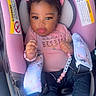 baby, child, car_seat, pink, clothing, hair_bow, hair_clip, denim, shoes, bracelet, necklace, infant, cute, portrait, indoor, seat_belt, accessory, person, smiling, young